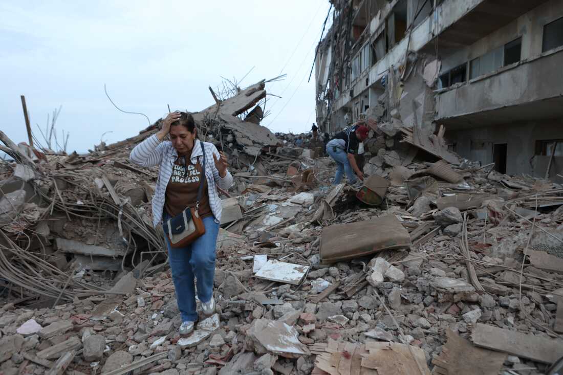 A woman walks through the rubble of collapsed buildings as others search the debris in the aftermath of the earthquake in Venezuela.